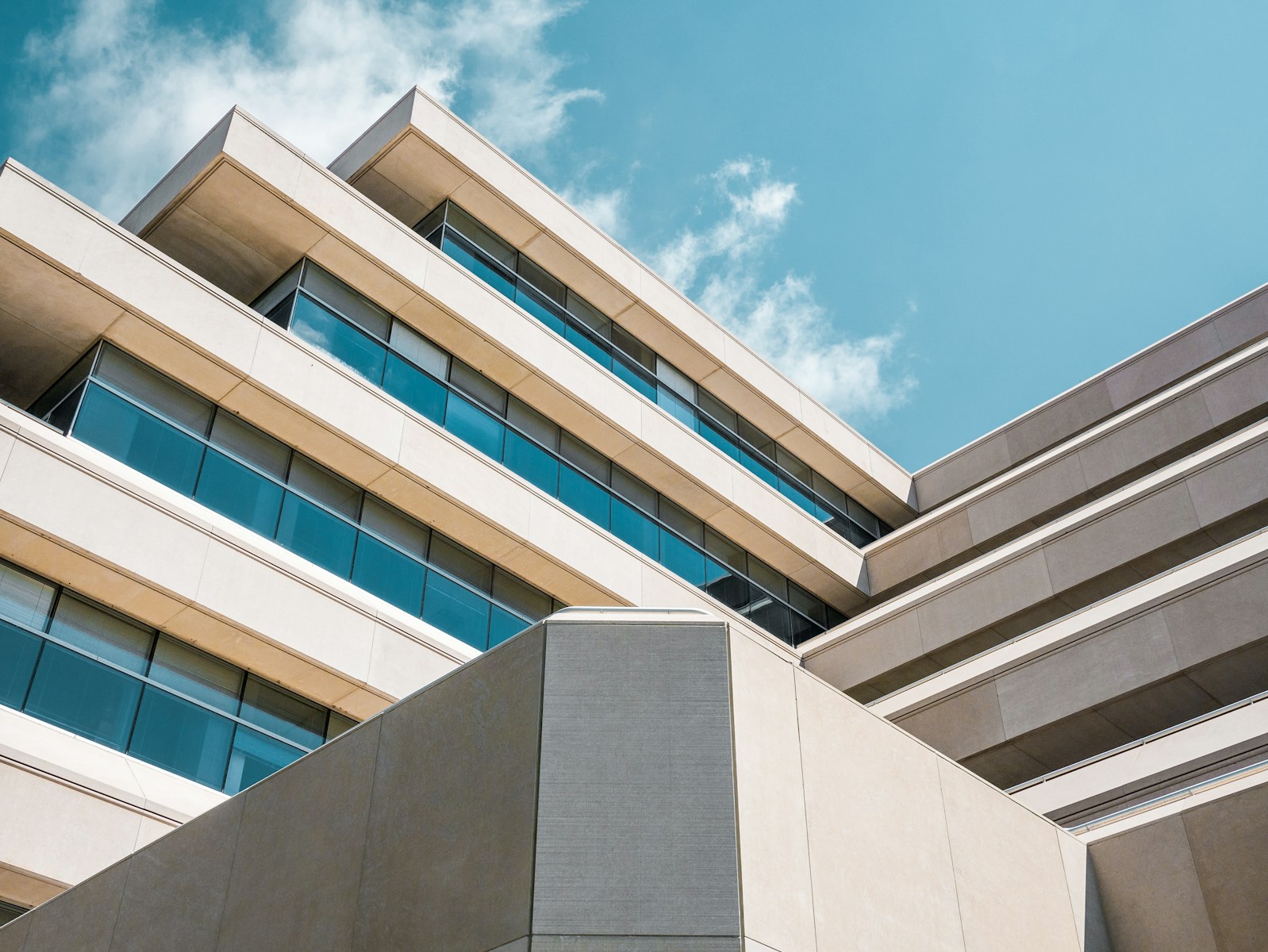 low angle photo of beige concrete building under cloudy sky, general liability